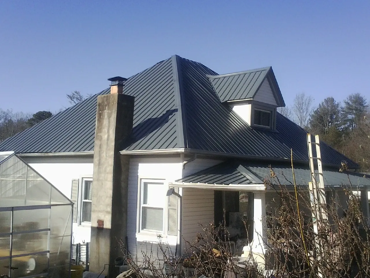 Dark blue standing seam metal roof on a white farmhouse with dormer — Slate & Tile Roof Repair by Roofing Brothers in Royal City