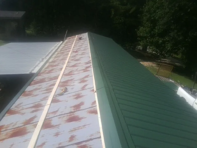Old rusted panels beside newly installed green metal roofing — Wind Damage Roof Repair by Roofing Brothers in Royal City