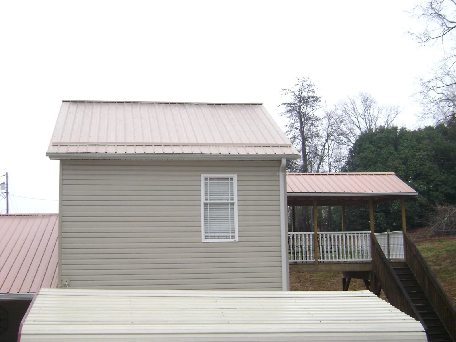 Tan metal roofs on a two story addition and attached porch, from a Roof Replacement job in Royal City