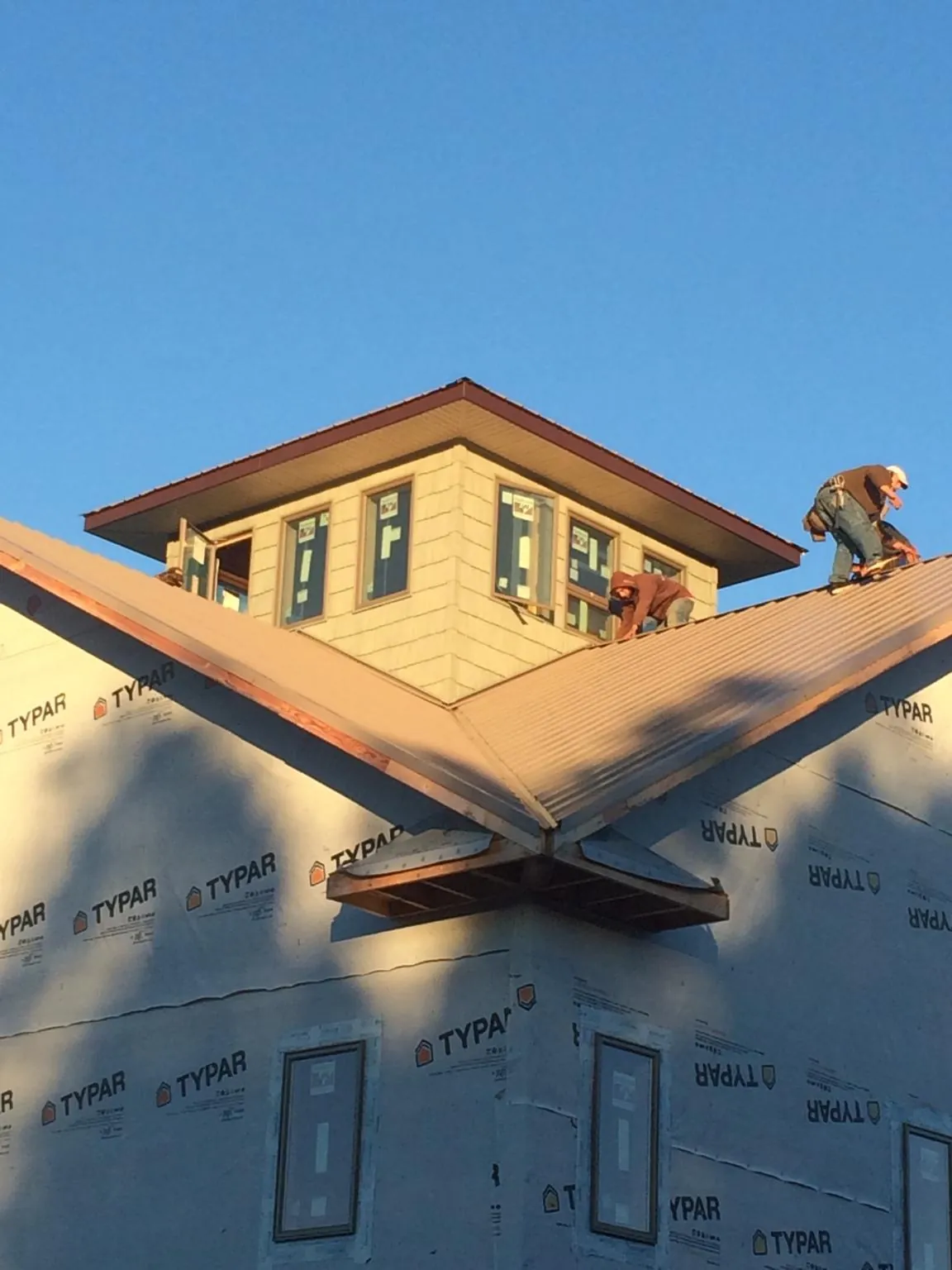 Roofers working around a rooftop cupola on a new metal roof at sunset — Roof Waterproofing in Royal City by Roofing Brothers